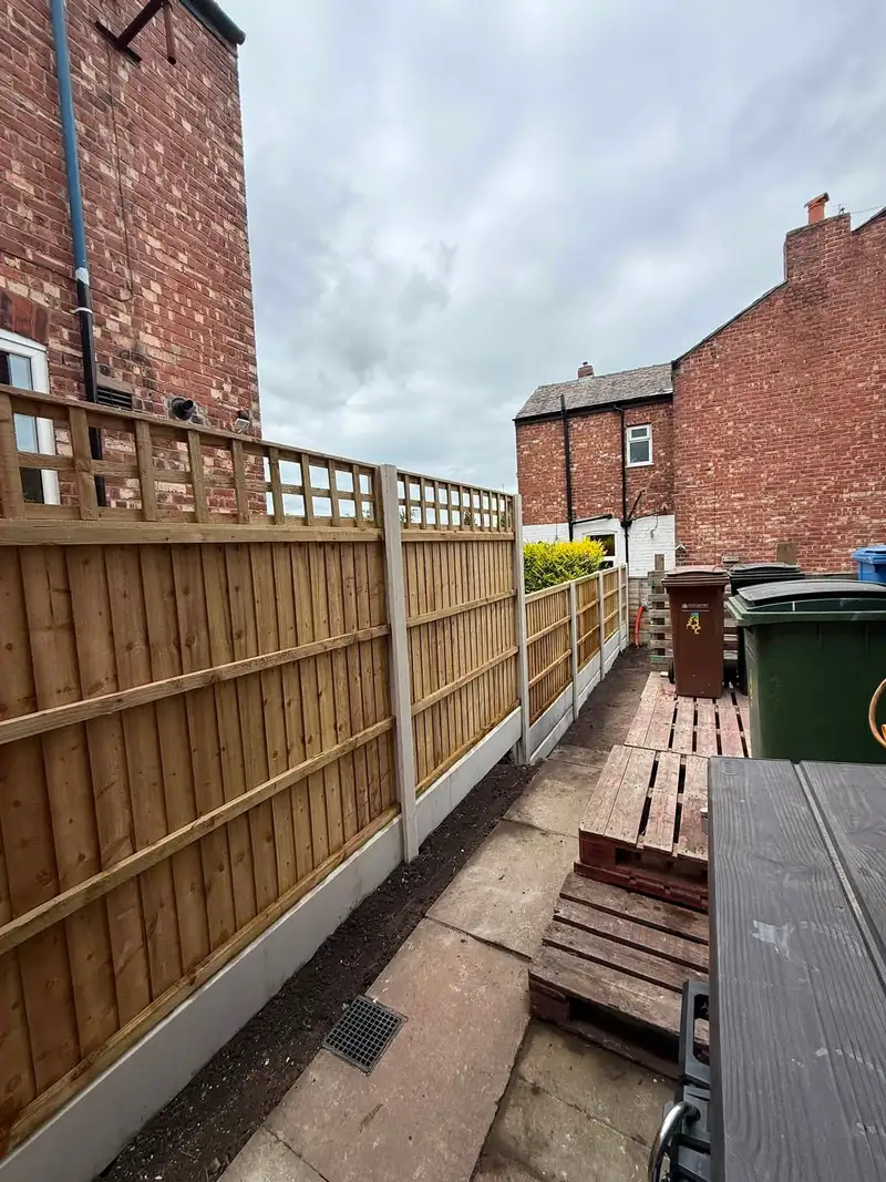 Long closeboard fence with trellis topper running down a terraced back passage