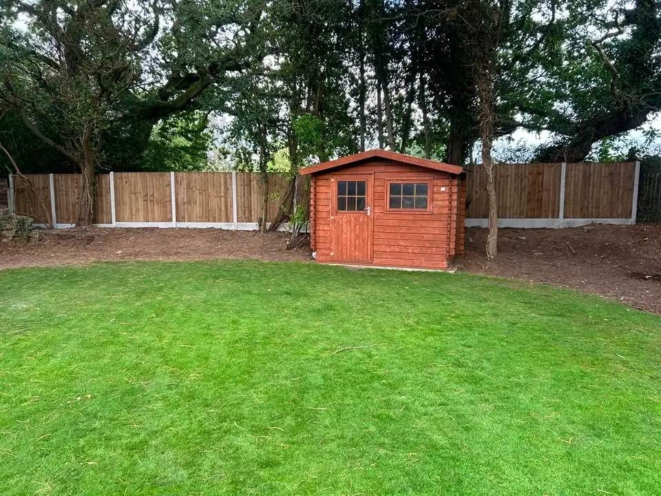 After: new panel fence with concrete posts running behind a red timber shed and lawn