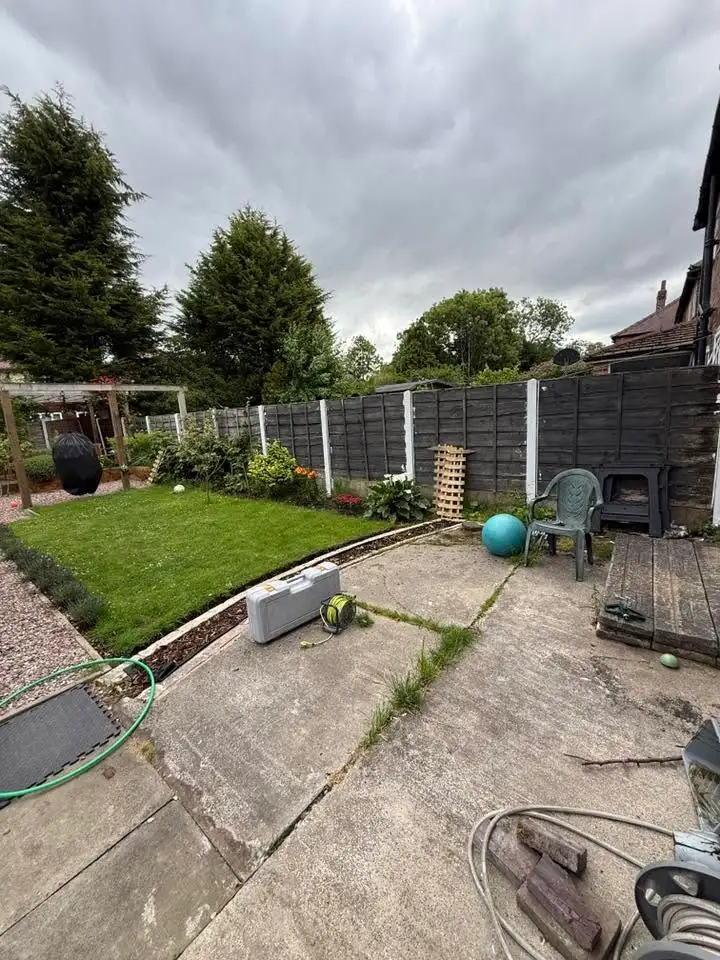 Fence painted black behind a small lawn and patio