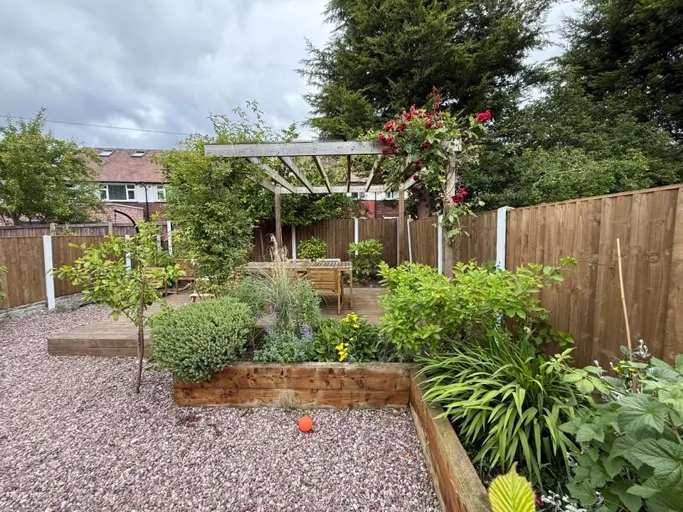 Finished garden with new fence panels behind raised beds and a pergola