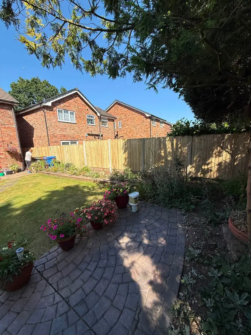 New fence along the edge of a lawn and patio at a modern brick house