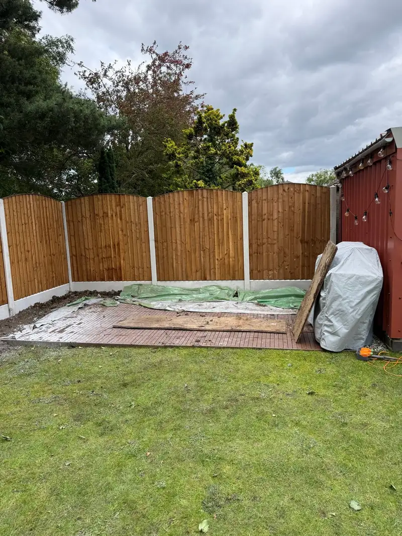 New fence panels between concrete posts in the corner of a lawned garden