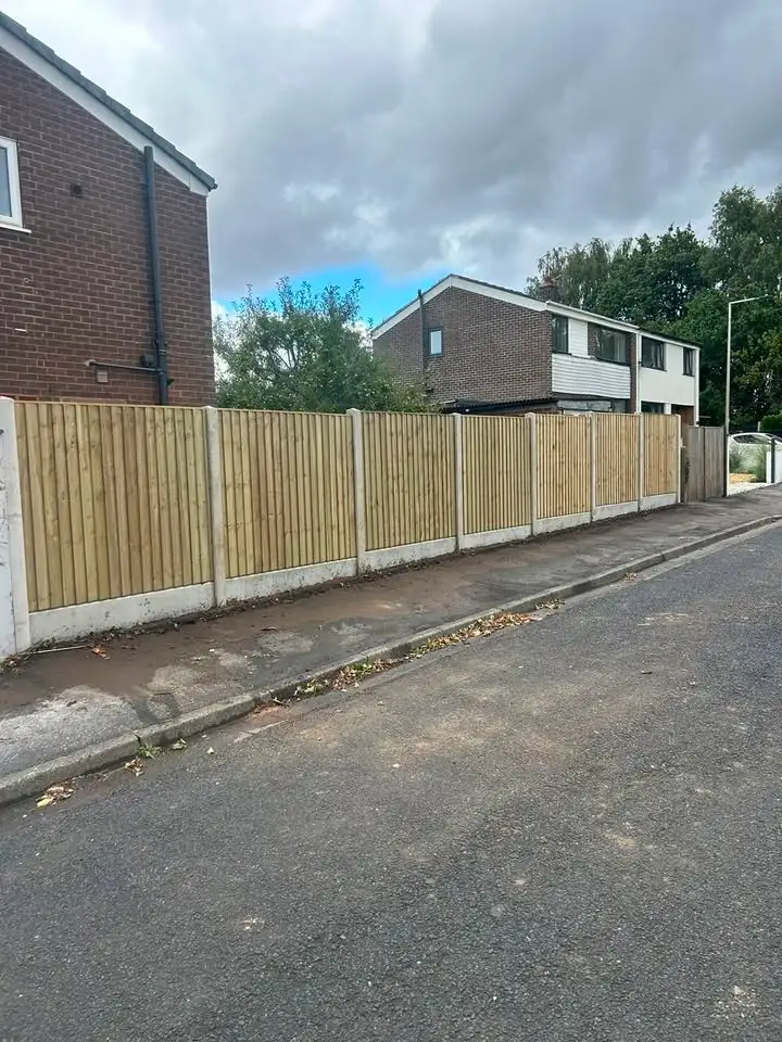Long panel fence with concrete posts along a residential road