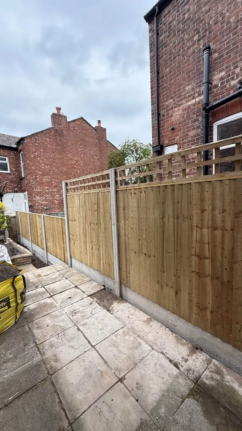 Closeboard fence with trellis topper beside a patio in a terraced garden